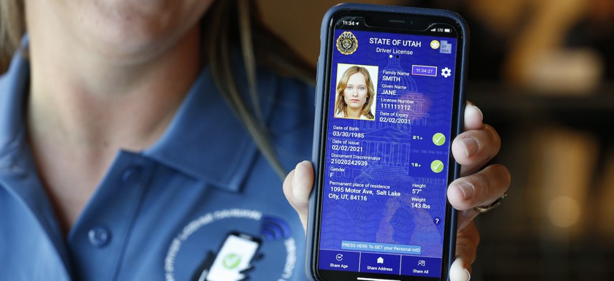 A Utah state worker displays a sample mobile drivers license at a 2021 event. Utah is currently one of nine states to offer mDLs. Some in Congress want more information on how digital IDs impact transportation security.
