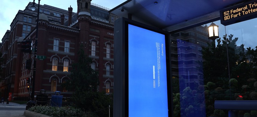 A sign in a Washington, D.C. bus shelter shows the Microsoft reboot blue screen four days after a faulty Crowdstrike update caused a worldwide technology outage. Experts say the impact would have been more widely felt in U.S. schools if it had occurred during the academic year.