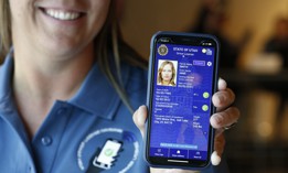 A Utah Department of Motor Vehicle employee shows a sample of a digital driver's license on a mobile phone at a demonstration in August 2021 in Salt Lake City. The Transportation Security Administration is finalizing plans to allow for the use of mDLs at airport security checkpoints.