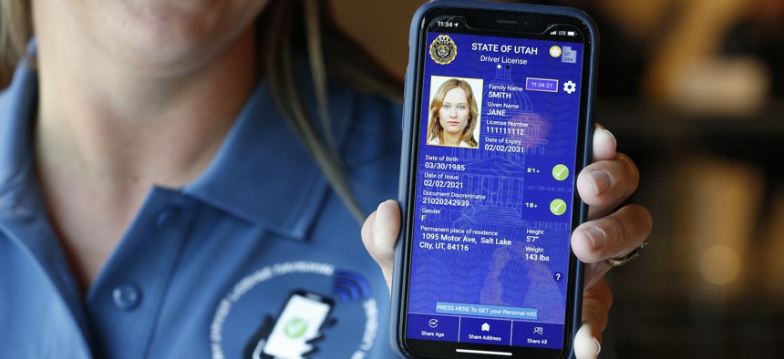 A Utah Department of Motor Vehicle employee shows a sample of a digital driver's license on a mobile phone at a demonstration in August 2021 in Salt Lake City. The Transportation Security Administration is finalizing plans to allow for the use of mDLs at airport security checkpoints.