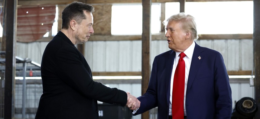 Elon Musk (L) shakes hands with former President Donald Trump back stage during a campaign rally at the Butler Farm Show grounds on October 05, 2024. The president-elect has vowed to create a government efficiency commission under Musk that will recommend "drastic reforms."