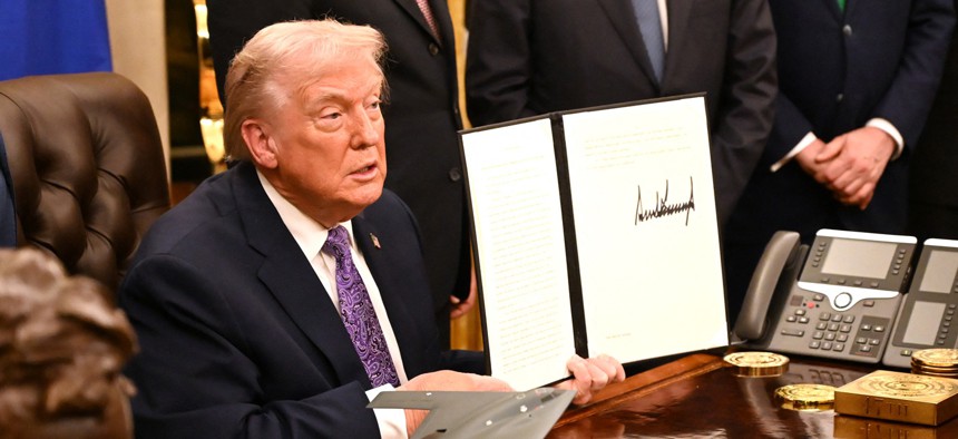 US President Donald Trump holds up his signed AI initiative during a signing ceremony in the Oval Office of the White House in Washington, DC, on December 11, 2025.