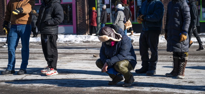 A person kneels near the site where 37-year-old Alex Pretti was allegedly shot and killed by federal agents on Jan. 24, 2026 in Minneapolis, Minnesota. Federal agents allegedly shot and killed Pretti, a south Minneapolis resident, amid a scuffle to arrest him. 
