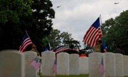 People gather in Marietta National Cemetery as four UH-60 Blackhawks from the Georgia National Guard 78th Aviation Troop Command perform a flyover on Memorial Day, May 25, 2020.