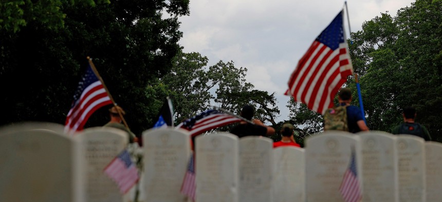People gather in Marietta National Cemetery as four UH-60 Blackhawks from the Georgia National Guard 78th Aviation Troop Command perform a flyover on Memorial Day, May 25, 2020.