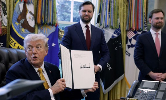 U.S. President Donald Trump holds up a document that he signed as Vice President JD Vance (C) and Federal Trade Commission Chairman Andrew Ferguson look on during a White House signing ceremony in the Oval Office of the White House on March 16, 2026 in Washington, DC. Trump signed an executive order to create a task force on fraud which will be lead by Vice President J.D. Vance.