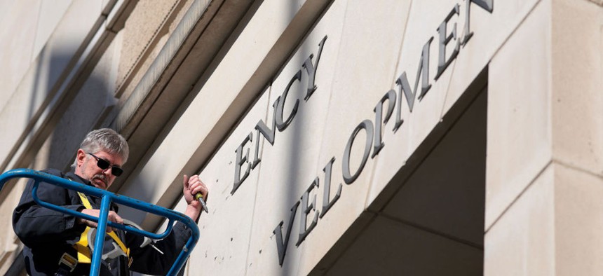 A worker removes the U.S. Agency for International Development sign on their headquarters on February 07, 2025 in Washington, DC. President Donald Trump and Elon Musk's Department of Government Efficiency (DOGE) abruptly shutdown the U.S. aid agency earlier this week leaving thousands unemployed and putting U.S. foreign diplomacy and aid programs in limbo.