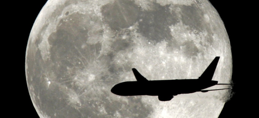 A jet plane passes in front of the full moon.