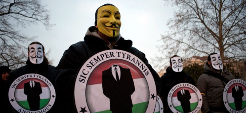Protestors wearing Guy Fawks masks hold the logos of the international hacker group Anonymous during a demonstration against online censorship laws.