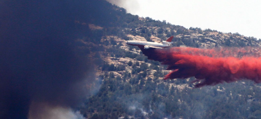 An aerial tanker drops fire retardant on a wildfires threatening homes near Yarnell, Ariz., Monday, July 1, 2013.