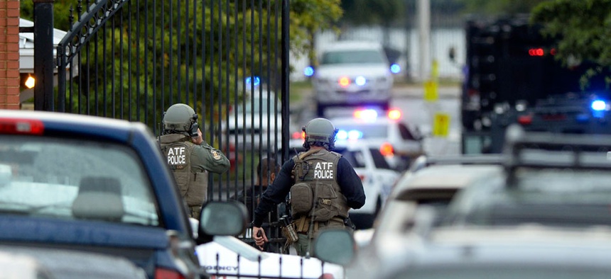 Law enforcement personnel walk through a gate into the Washington Navy Yard.