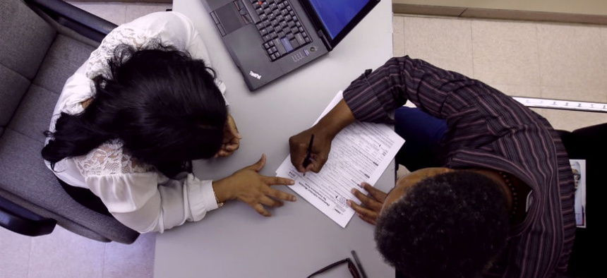 Clinical applications counselor Rachael Richardson, left, works with Louis Peters at the Henry J. Austin Health Center, in Trenton, N.J., as he and others fill out papers to sign up for new plans through the health insurance exchange.