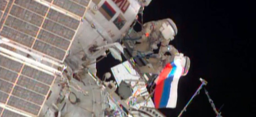 Cosmonauts wave a Russian flag near the end of their spacewalk outside the International Space Station.