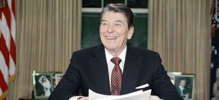 President Ronald Reagan poses for photographers in the Oval Office.