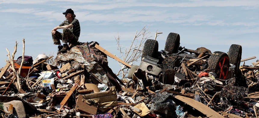 A man sits atop a pile of rubble after a tornado came through Oklahoma in May.