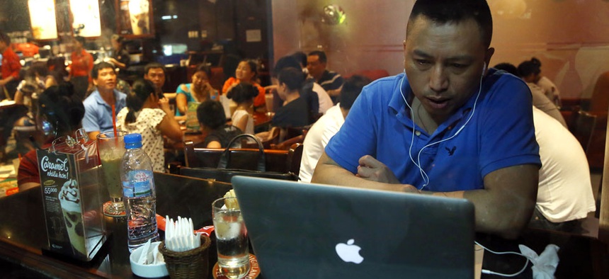 A Vietnamese man uses a laptop to go online by a 3G device inserted into a USB pot at a cafe in Ha Noi, Viet Nam.