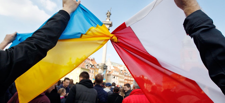 People hold tied Polish, right, and Ukrainian flags during a demonstration supporting the opposition movement in Ukraine, in Warsaw, Poland.