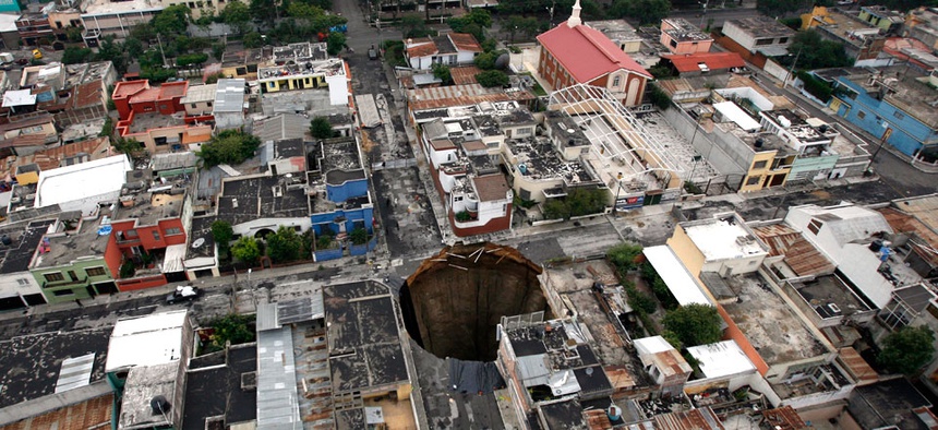 A sinkhole covers a street intersection in downtown Guatemala City, Wednesday, June 2, 2010.