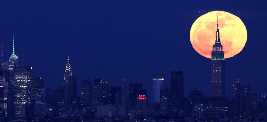 A full moon rises behind the Empire State Building in New York.