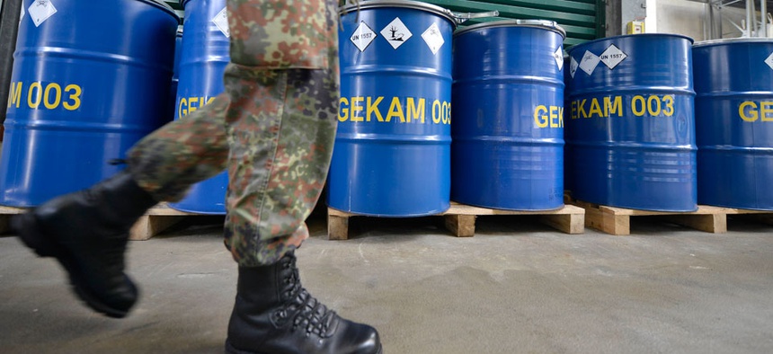 An army officer walks past barrels with chemical waste at the German state-run company GEKA, specialized in the disposal of hazardous materials. The company is tasked to destroy waste material from dismantled Syrian chemical weapons.