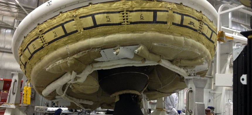 A saucer-shaped test vehicle holding equipment for landing large payloads on Mars in the Missile Assembly Building at the U.S Navy's Pacific Missile Range Facility.
