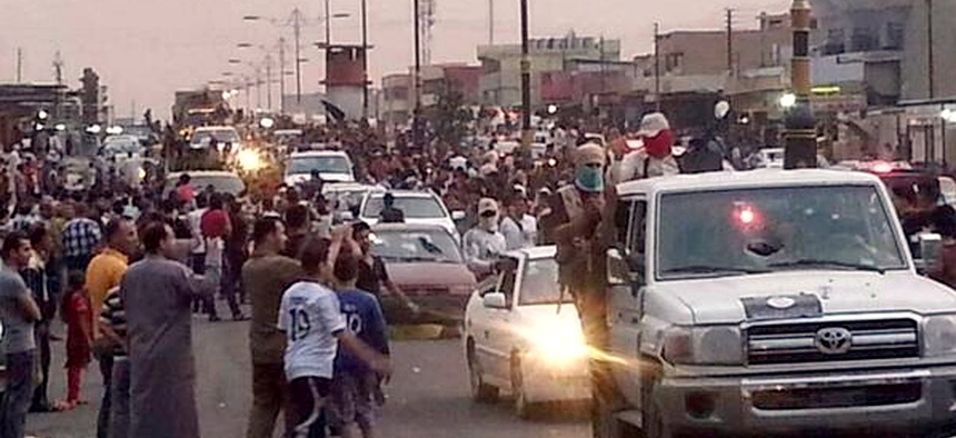 ISIS militants parade down a main road in Mosul, Iraq.