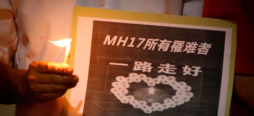 A man holds a sign which reads " MH17 Victims Rest In Peace" during a candlelight vigil for the victims who were on board the Malaysia Airlines jetliner.