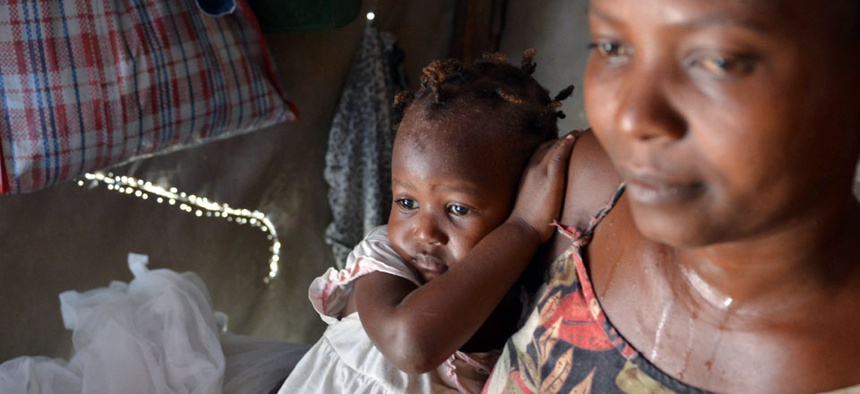 Delimene Saint Lise holds her 2-month-old daughter Gisline inside their tent home in the Delmas section of Port-au-Prince as the child suffers with Chikungunya, a newly arrived mosquito-borne illness.