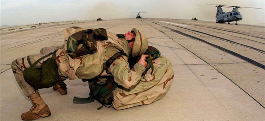 Deployed from USS Bataan and arriving in Afghanistan with a heavy backpack, a Marine with the 26th Marine Expeditionary Unit (Special Operations Capable), dons his backpack by laying his back on it.