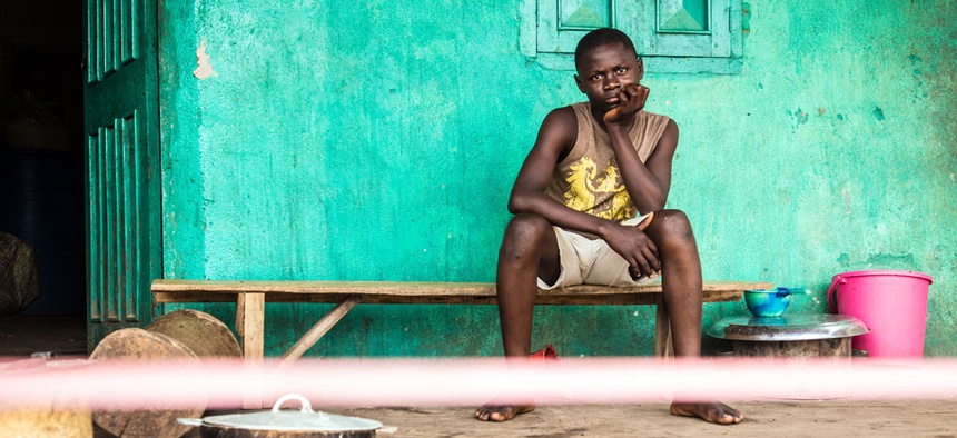 A youth under quarantine sits behind a cordon outside his house in Moyamba town on the outskirts of Freetown, Sierra Leone.