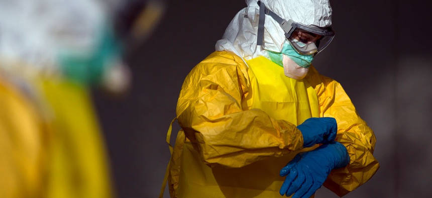 Licensed clinician Margaret Chilcott removes her outer gloves before disrobing and sanitizing during ebola preparation training on Monday, Oct. 6, 2014, in Anniston, Ala.