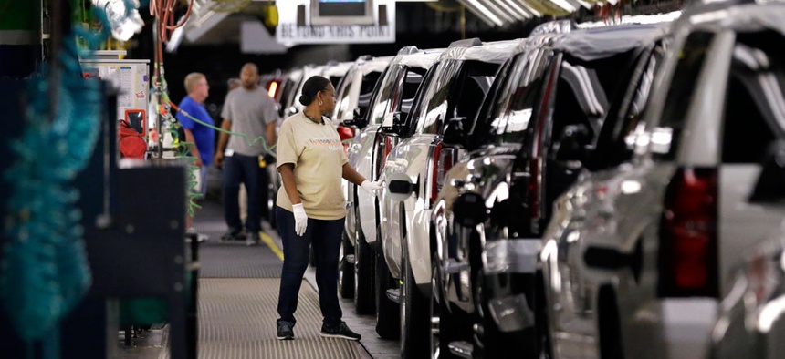 An auto worker inspects finished SUVs coming off the assembly line at the General Motors auto plant in Arlington, Texas.