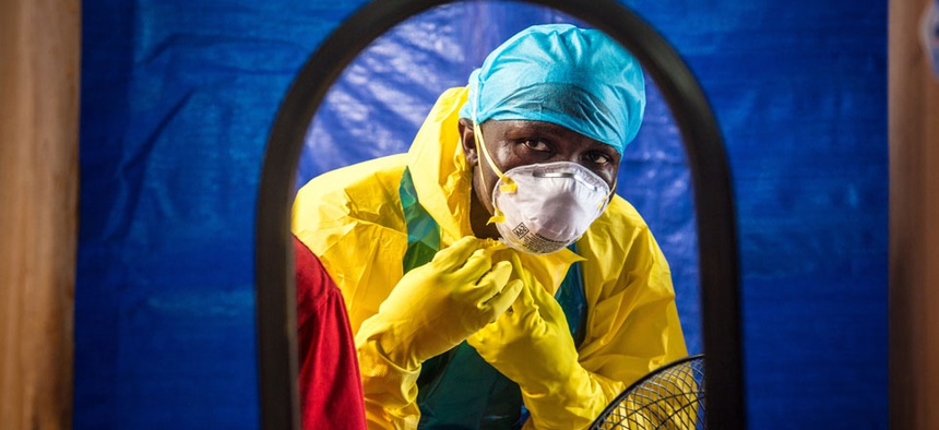 A healthcare worker dons protective gear before entering into an Ebola treatment centre in the west of Freetown, Sierra Leone.