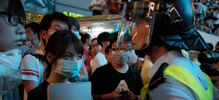Riot police officers stand guard against protesters at a main road in the Mong Kok district of Hong Kong Friday, Oct. 17, 2014.