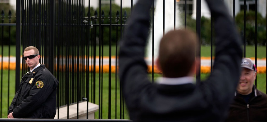 A Secret Service police officer keeps an eye on visitors on the sidewalk in front of the White House in Washington.