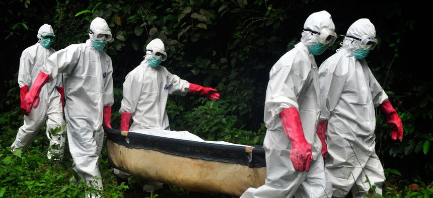 A burial team in protective gear carry the body of woman suspected to have died from the Ebola virus in Monrovia, Liberia.