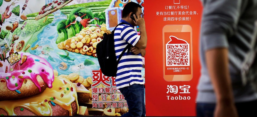 A Chinese man talks on a mobile phone as he walks past a Taobao's mobile app advertisement billboard on display inside a subway station in Beijing.