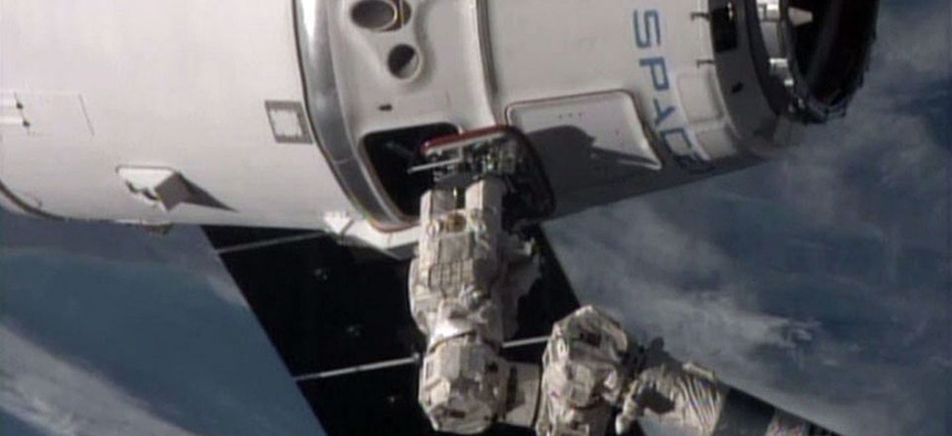 The International Space Station's robotic arm, lower right, operated by station commander Butch Wilmore, reaches for the SpaceX Dragon spacecraft.