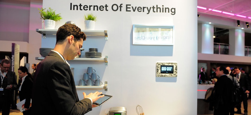 A man checks his device in front of a banner "Internet of Everything" at the Mobile World Congress.