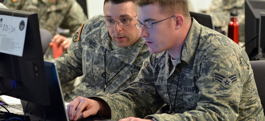 Army Sgt. 1st Class Michael Deblock, Vermont Army National Guard Computer Network Defense Team, left, discusses new ways to make the exercise more challenging for cyber defenders with a fellow Red Cell team member during the 2014 Cyber Shield exercise.
