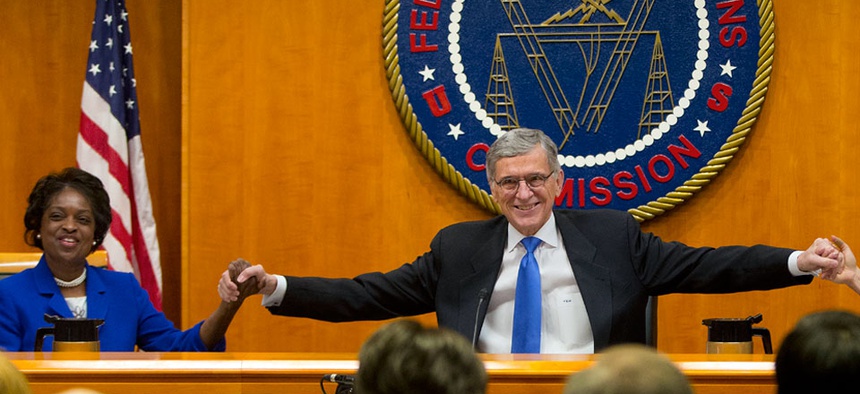 FCC Chairman Tom Wheeler joins hands with FCC Commissioner Mignon Clyburn before the start of their open hearing and vote on Net Neutrality.