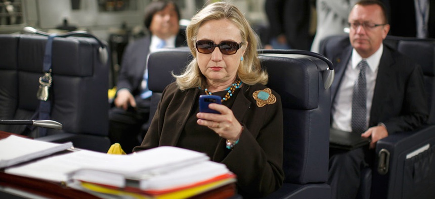 Then-Secretary of State Hillary Rodham Clinton checks her Blackberry from a desk inside a C-17 military plane upon her departure from Malta.