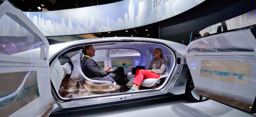 Attendees sit in the self-driving Mercedes-Benz F 015 concept car at the Mercedes-Benz booth at the International CES in Las Vegas.
