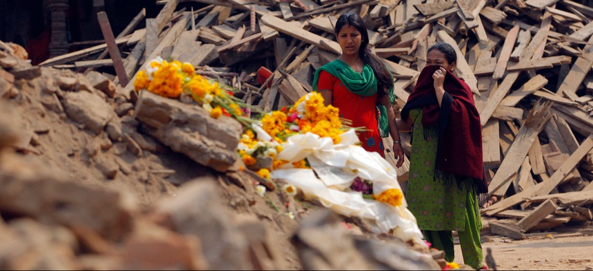 Nepalese women look at floral tributes placed in memory of victims killed in the earthquake, at Basantapur Durbar Square in Kathmandu, Nepal, Thursday, May 7, 2015.