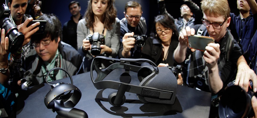 Photographers take pictures of the new Oculus Rift virtual reality headset and touch input device.