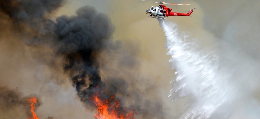 A Los Angeles City Fire helicopter drops water on flames, Wednesday, June 24, 2015, in Santa Clarita, Calif.