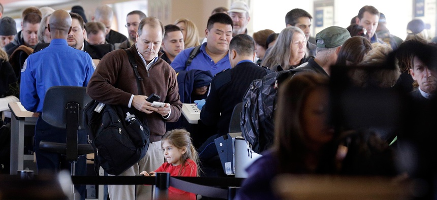Travelers wait in line to check in at a security checkpoint area at Midway International Airport, Friday, Nov. 21, 2014, in Chicago.
