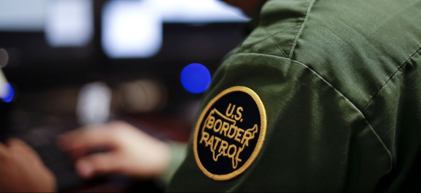 In this June 5, 2014 photo, a Border Patrol agent uses a headset and computer to conduct a long distance interview by video with a person arrested crossing the border in Texas, from a facility in San Diego.