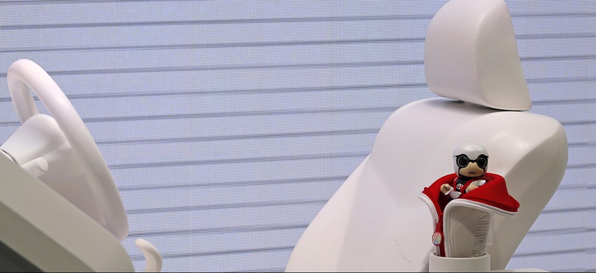 Toyota Motor Corp.'s KIROBO MINI, a compact sized humanoid communication robot, sits near the driver's seat and steering wheel during the media preview of the Tokyo Motor Show.