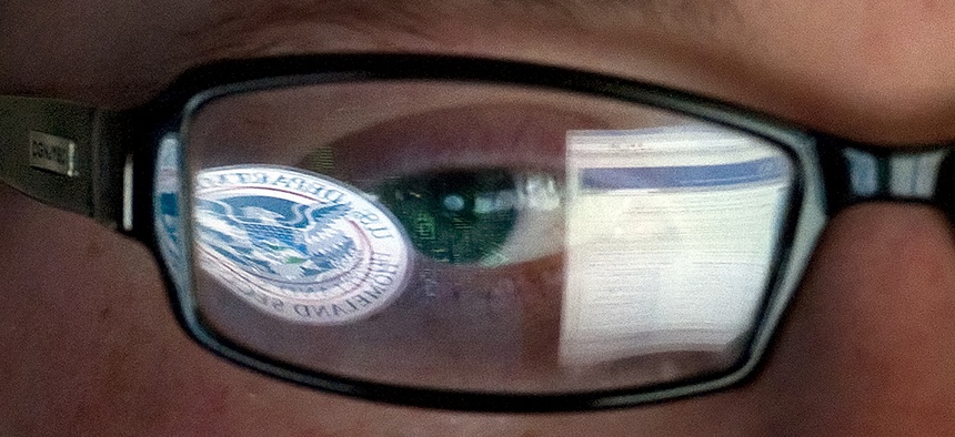 A reflection of the Department of Homeland Security logo is seen reflected in the glasses of a cyber security analyst in the agency's watch and warning center.